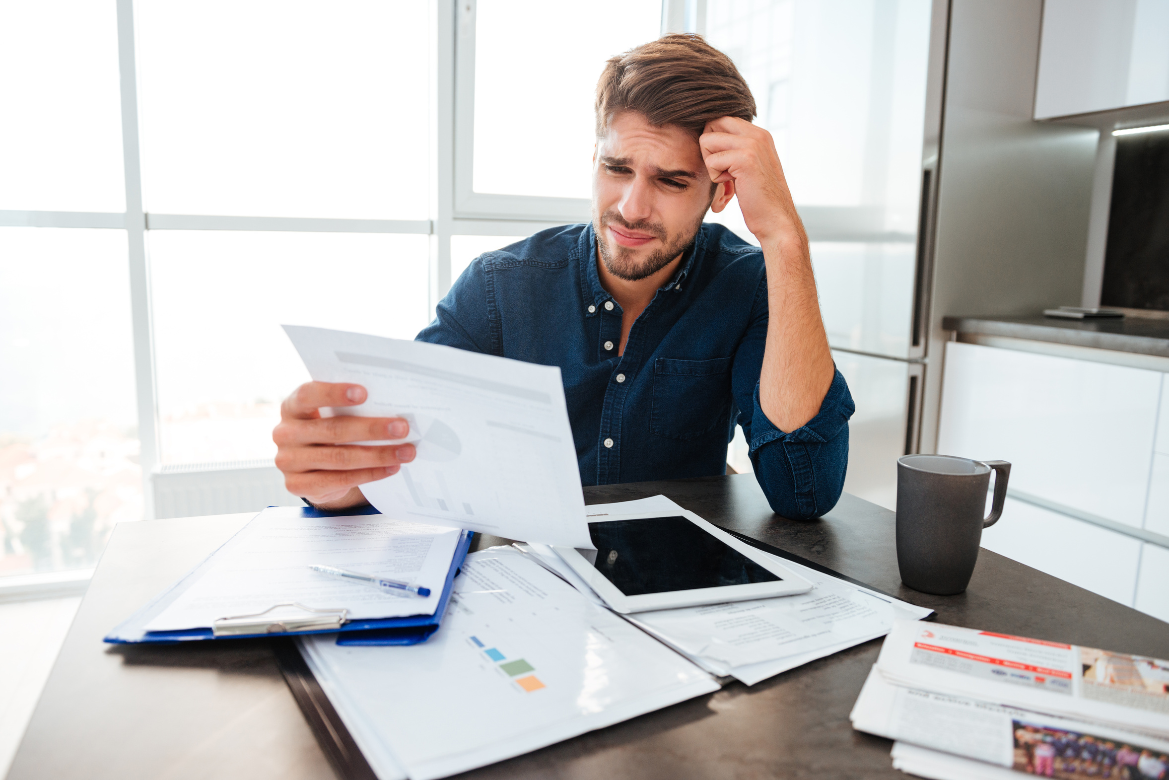 Concerned man looking over tax paperwork at a desk